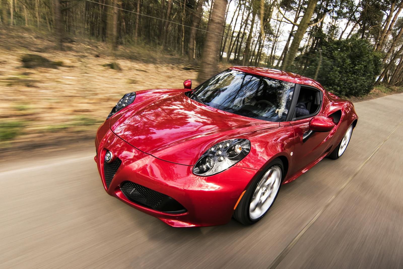 auto, sleek red sports car driving fast on a forest road, showcasing speed and luxury.